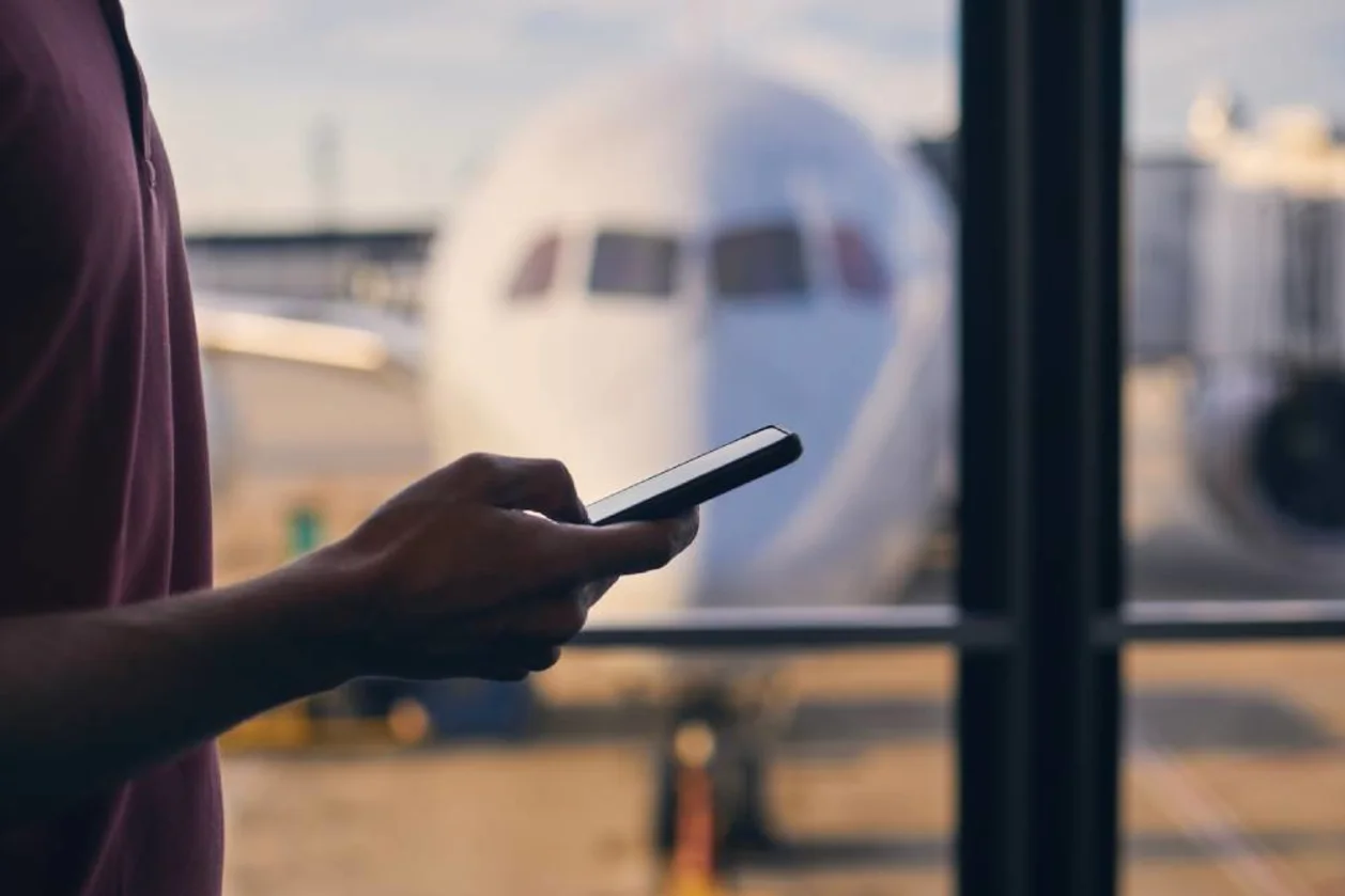 Silhouette of passenger using smartphone at airport